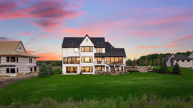 back house at dusk with a yard and a balcony