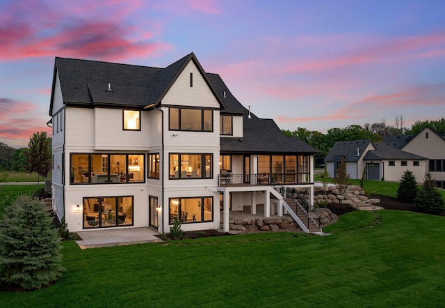 back house at dusk with a lawn and a patio area