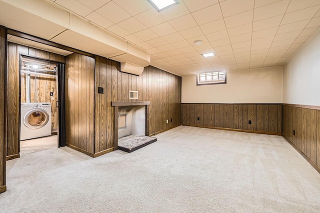 basement with light colored carpet, washer / clothes dryer, and wood walls