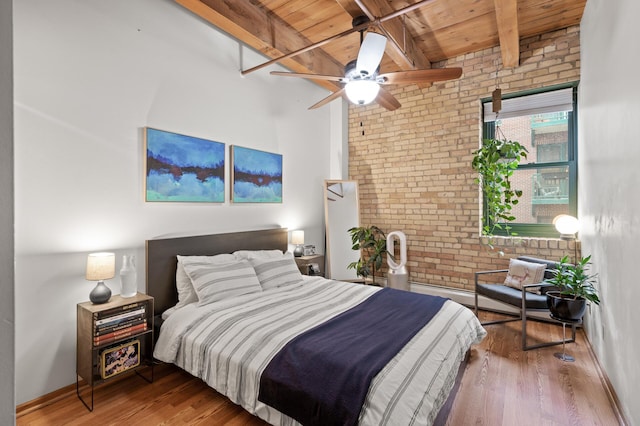 bedroom featuring wood ceiling, ceiling fan, hardwood / wood-style floors, brick wall, and beamed ceiling