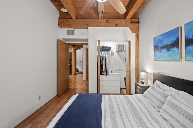 bedroom featuring beamed ceiling, ceiling fan, wooden ceiling, light wood-type flooring, and a closet