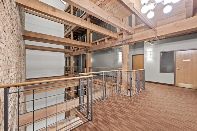 hallway featuring a towering ceiling, wood-type flooring, and beamed ceiling