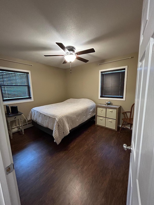 bedroom with dark hardwood / wood-style flooring, a textured ceiling, and ceiling fan