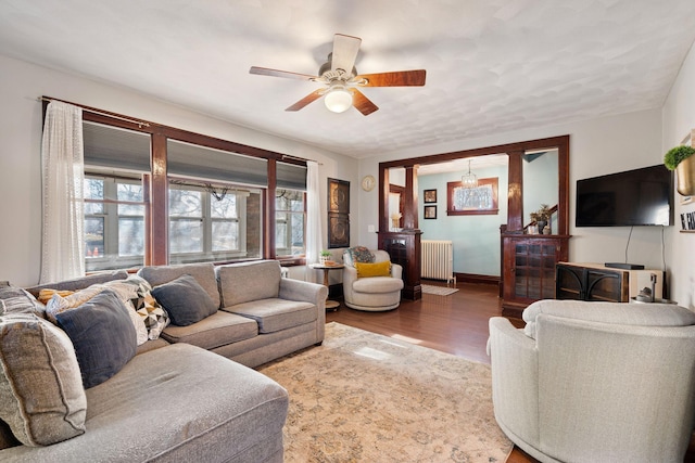 living area featuring baseboards, wood finished floors, a ceiling fan, and radiator