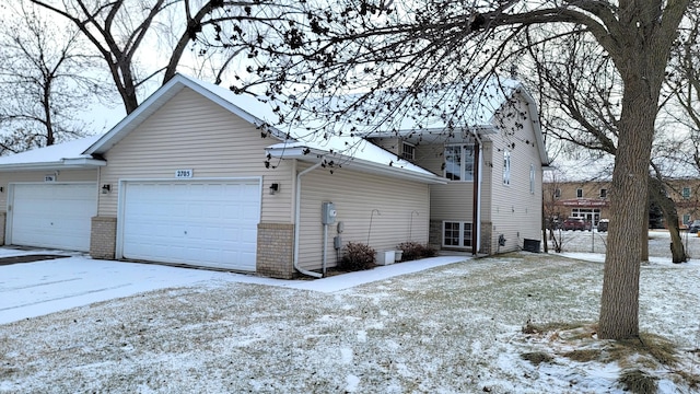 snow covered property with a garage