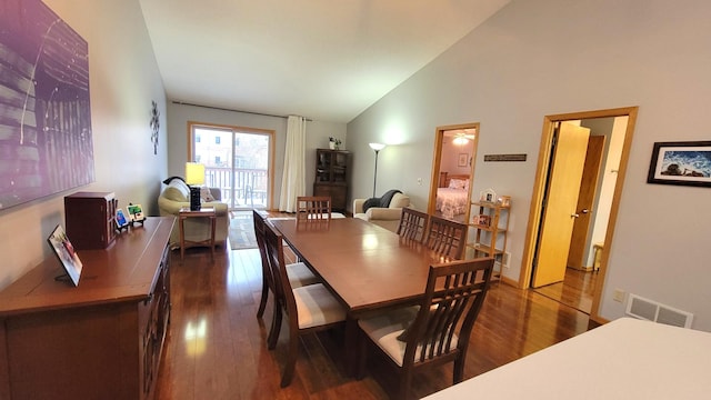 dining area featuring high vaulted ceiling and dark hardwood / wood-style flooring