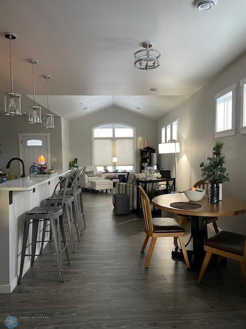 dining area with dark wood-type flooring and vaulted ceiling