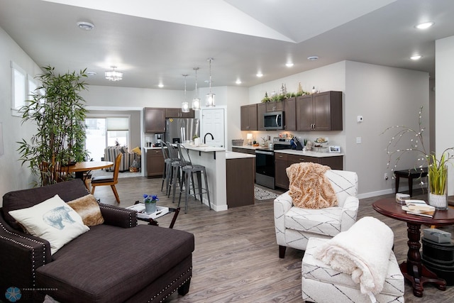 living room featuring hardwood / wood-style floors, vaulted ceiling, and sink