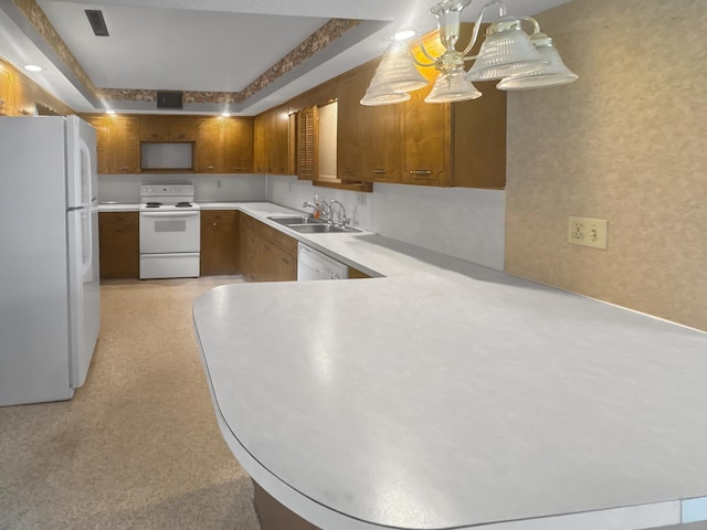 kitchen featuring white appliances, kitchen peninsula, sink, and hanging light fixtures