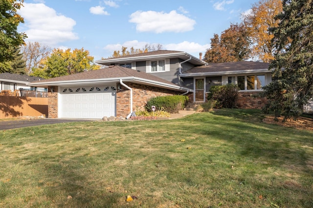 tri-level home featuring brick siding, fence, aphalt driveway, a front yard, and an attached garage