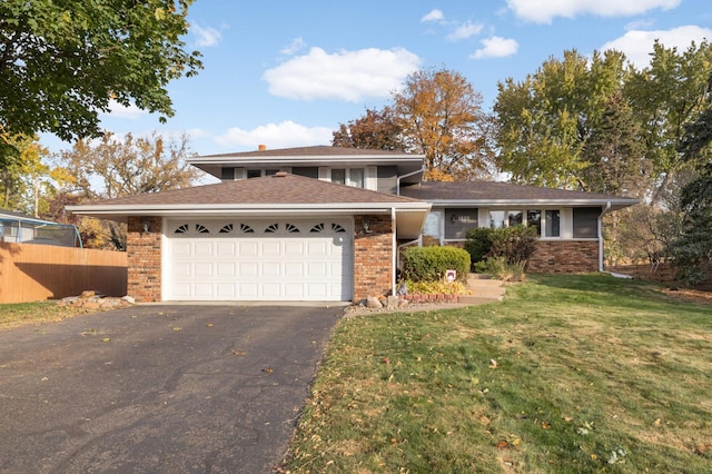 view of front of property featuring brick siding, driveway, a front lawn, and fence