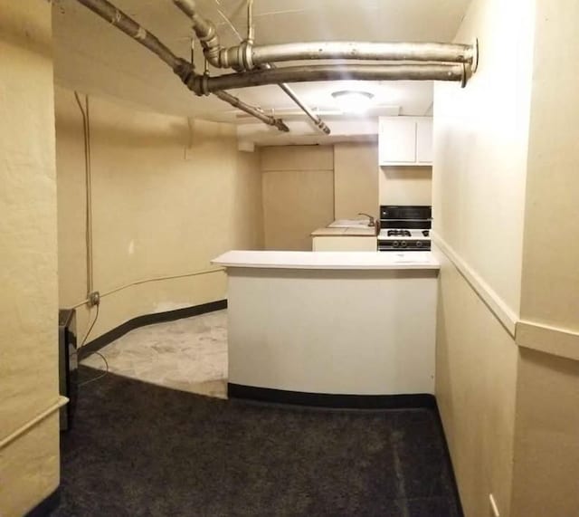 kitchen with stove, sink, and white cabinets