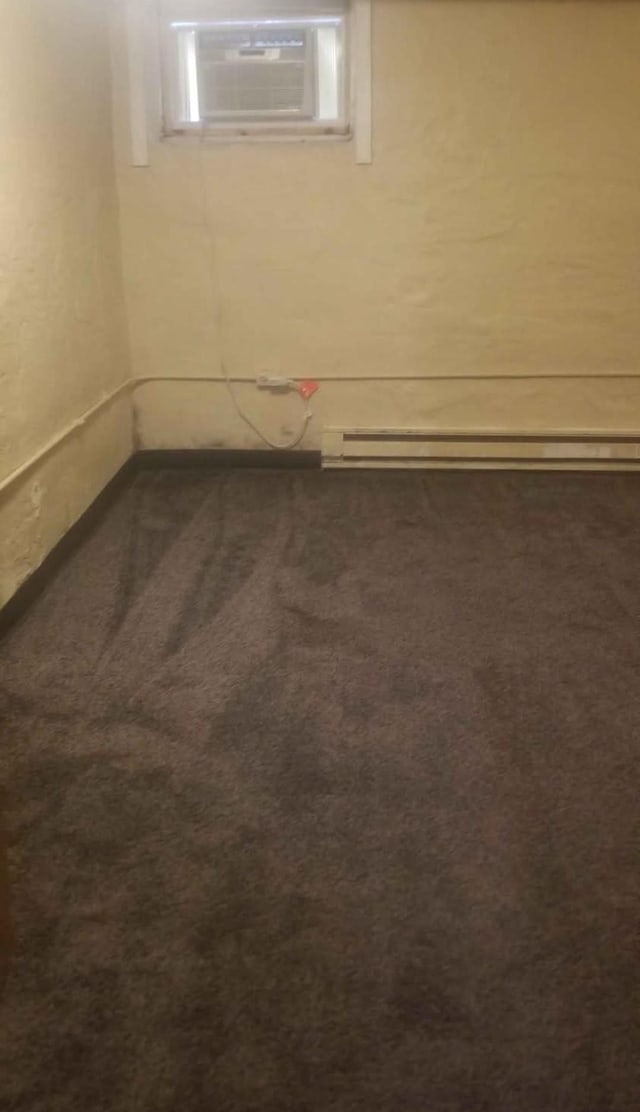 carpeted empty room featuring a baseboard heating unit