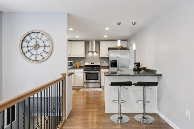 1524 Mulberry St, Taylors Falls, MN 55084 - kitchen with stainless steel appliances, wall chimney range hood, white cabinets, wood finished floors, and recessed lighting