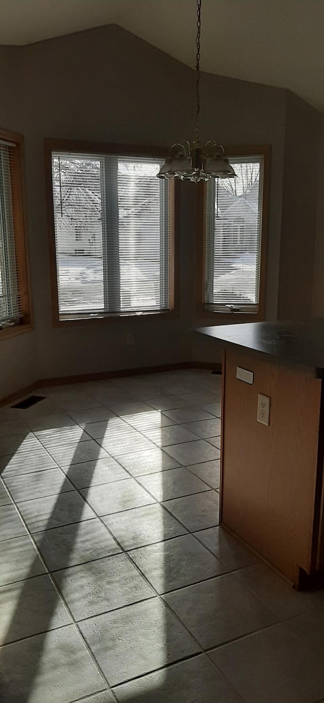 unfurnished dining area featuring lofted ceiling, a notable chandelier, and light tile patterned flooring