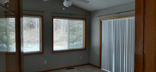 empty room featuring lofted ceiling, plenty of natural light, ceiling fan, and carpet