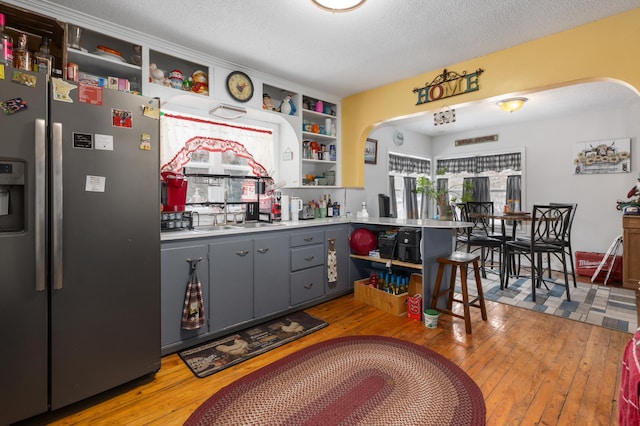 kitchen featuring gray cabinetry, stainless steel fridge, a textured ceiling, and light hardwood / wood-style flooring