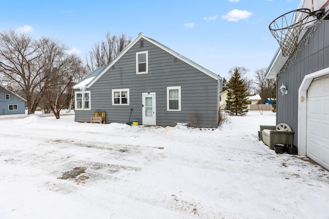 snow covered rear of property featuring a garage