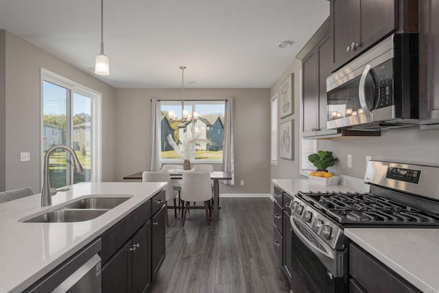 kitchen with decorative light fixtures, sink, a notable chandelier, stainless steel appliances, and dark wood-type flooring