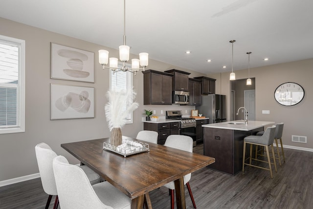 dining area with an inviting chandelier, sink, and dark wood-type flooring