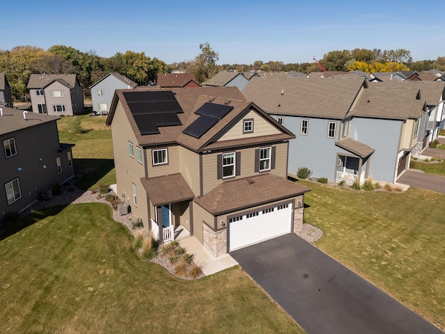 view of front of property with a garage, a front yard, and solar panels