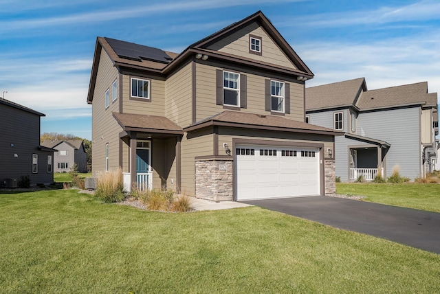 view of front of home featuring central AC unit, a garage, a front lawn, and solar panels