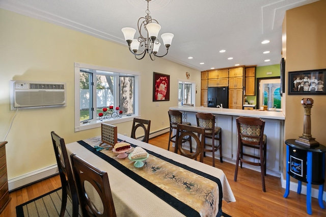 dining area with a baseboard radiator, light wood-type flooring, a chandelier, and a wall unit AC