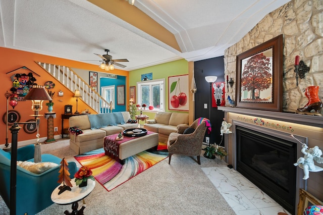 living room featuring ceiling fan, a fireplace, and a textured ceiling