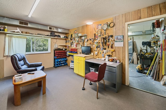 office with a workshop area, a textured ceiling, and wood walls