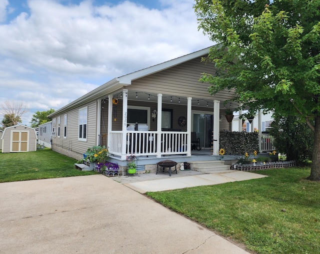 view of front of home featuring an outdoor fire pit, covered porch, an outdoor structure, a shed, and a front lawn