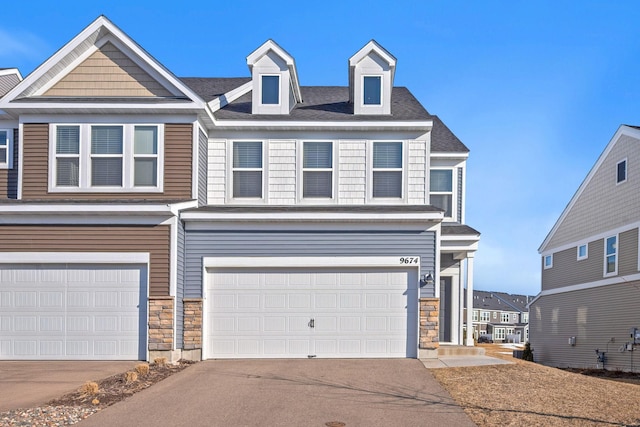 view of front of house with aphalt driveway, stone siding, and an attached garage