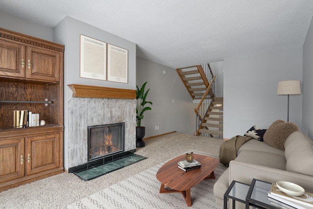 living room featuring light colored carpet, a tile fireplace, and a textured ceiling