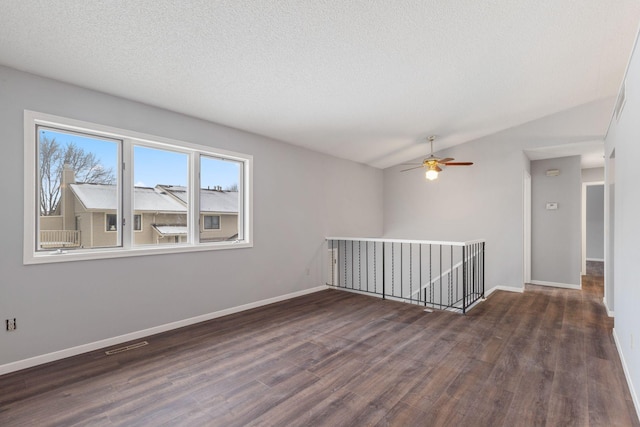 spare room featuring ceiling fan, dark hardwood / wood-style flooring, vaulted ceiling, and a textured ceiling