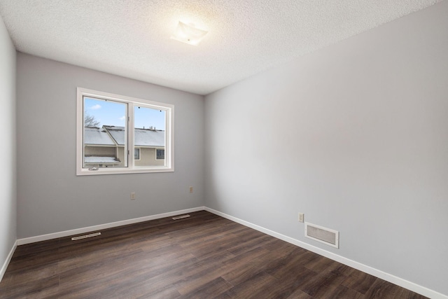 empty room with dark hardwood / wood-style floors and a textured ceiling