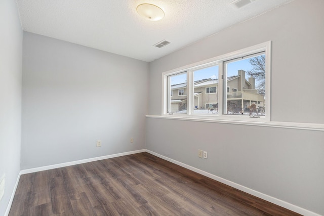 spare room featuring dark wood-type flooring and a textured ceiling