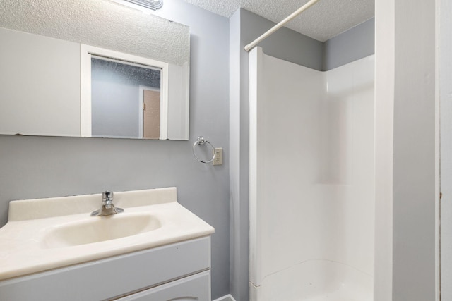 bathroom featuring vanity, a shower, and a textured ceiling