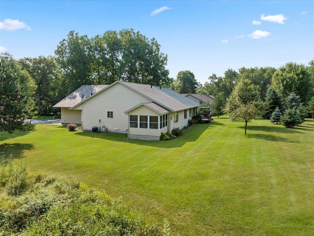 rear view of property featuring central AC unit and a lawn