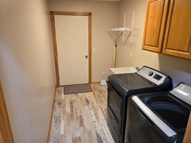 washroom with cabinets, washer and dryer, sink, and light hardwood / wood-style floors