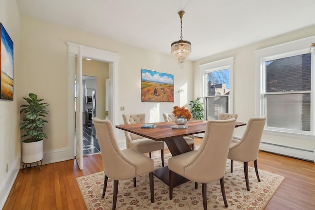 dining area featuring a notable chandelier, light wood-type flooring, and baseboard heating