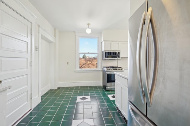 kitchen with decorative light fixtures, dark tile patterned floors, white cabinets, and appliances with stainless steel finishes