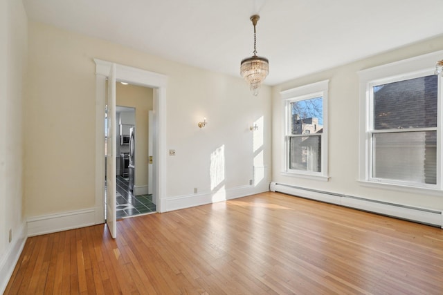 interior space featuring a baseboard heating unit, a notable chandelier, hardwood / wood-style flooring, and baseboards