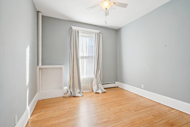 empty room featuring light wood-style floors, a baseboard heating unit, baseboards, and a ceiling fan