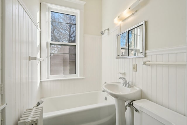 bathroom with wainscoting, toilet, and radiator