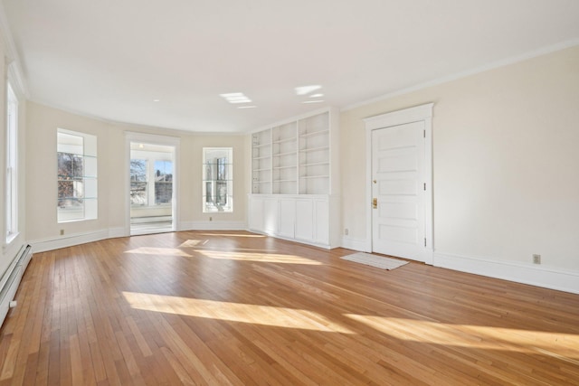 empty room featuring baseboards, baseboard heating, built in features, and light wood-style floors