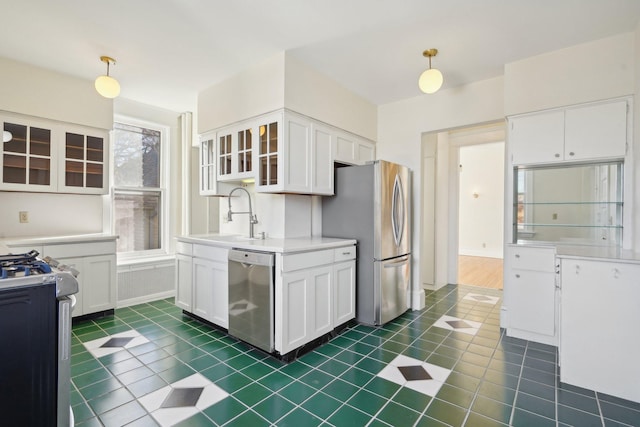 kitchen with hanging light fixtures, appliances with stainless steel finishes, glass insert cabinets, and white cabinetry