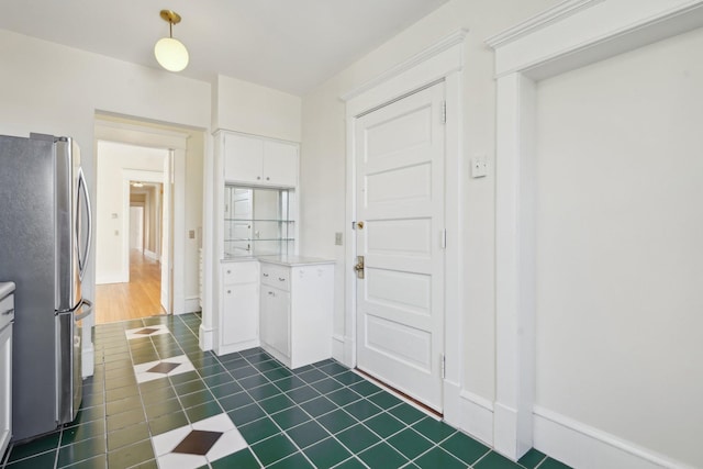 interior space with light countertops, freestanding refrigerator, white cabinetry, and baseboards