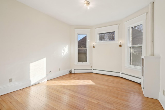 spare room with light wood-type flooring, a wealth of natural light, and baseboards