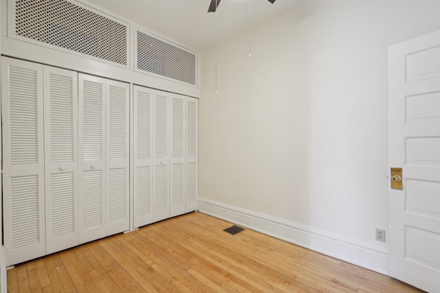 unfurnished bedroom with hardwood / wood-style floors, a closet, visible vents, and baseboards