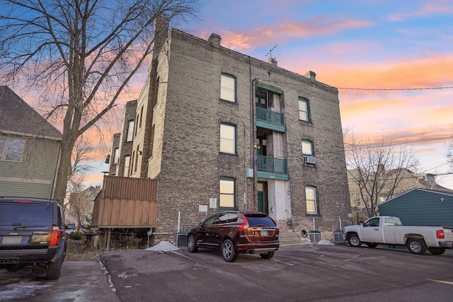 view of building exterior featuring uncovered parking and cooling unit