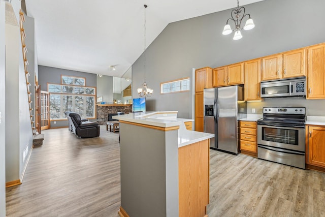 kitchen with high vaulted ceiling, decorative light fixtures, stainless steel appliances, a center island with sink, and an inviting chandelier